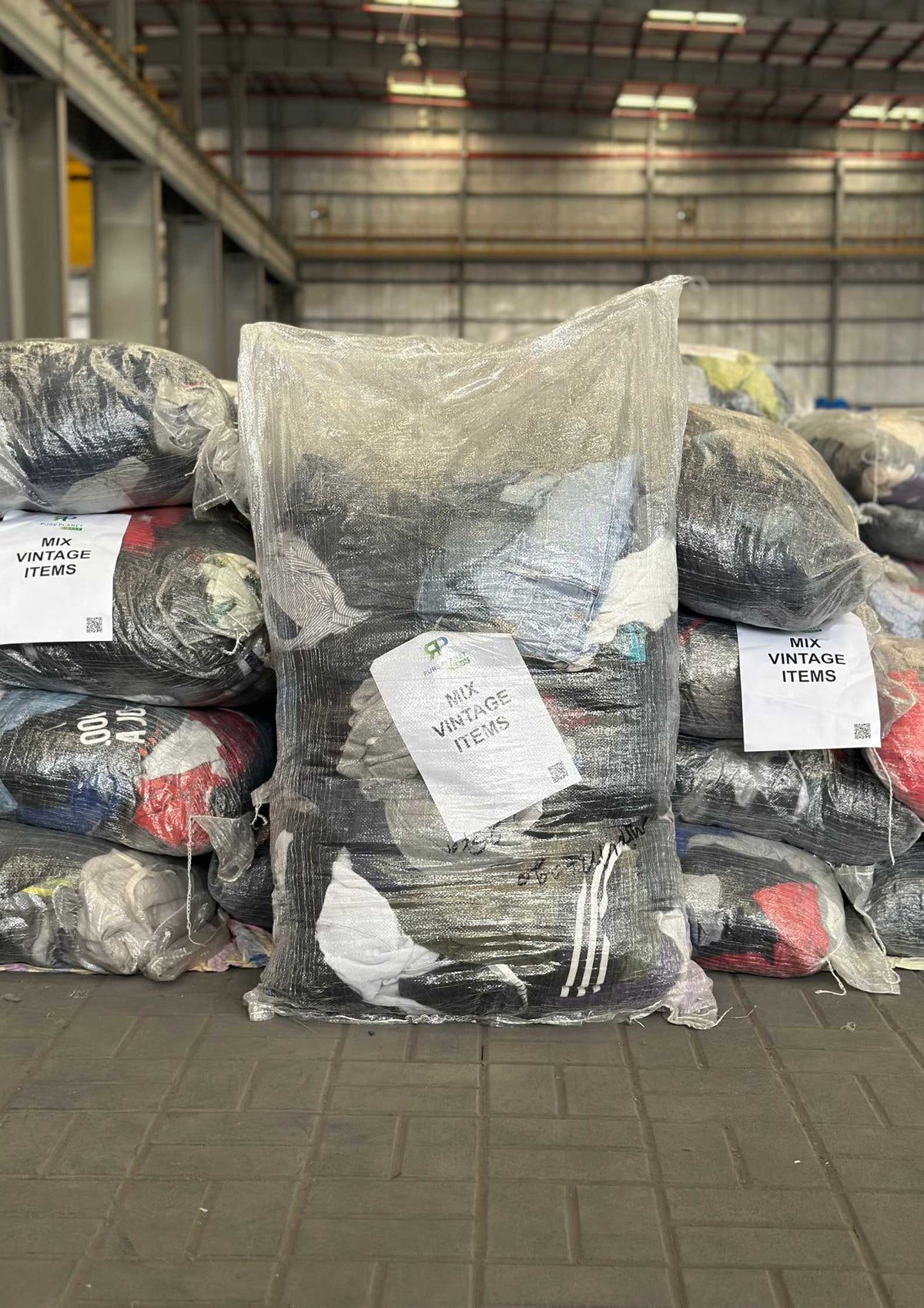 25kg wholesale sack of mixed branded vintage clothing containing folded sweatshirts, jackets, and knits.